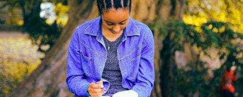 Woman writing a book in a park